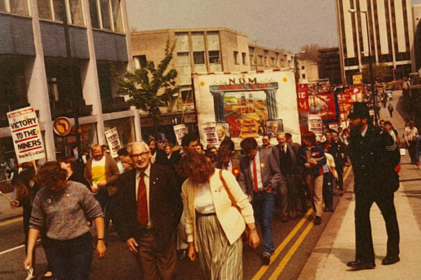 A march with trade union banners, and a policman looking on.